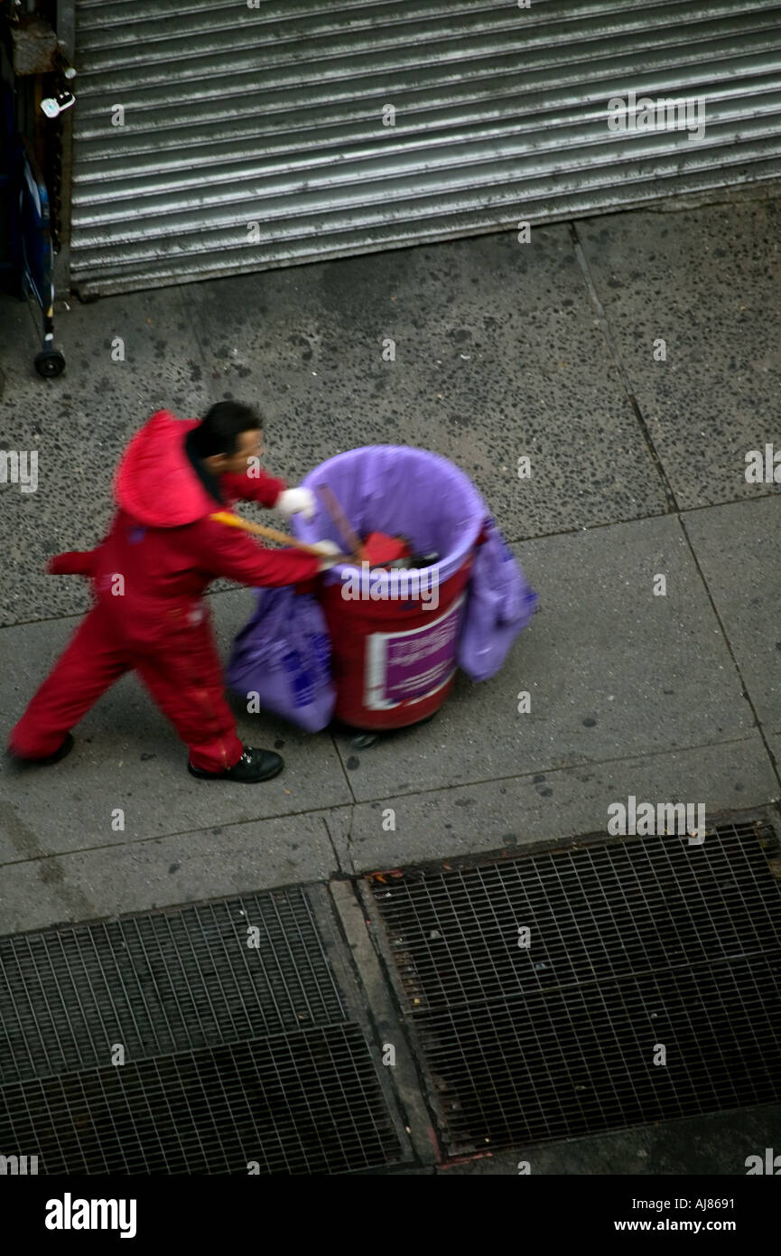 City worker pushes garbage can along sidewalk Midtown Manhattan New York NY Stock Photo