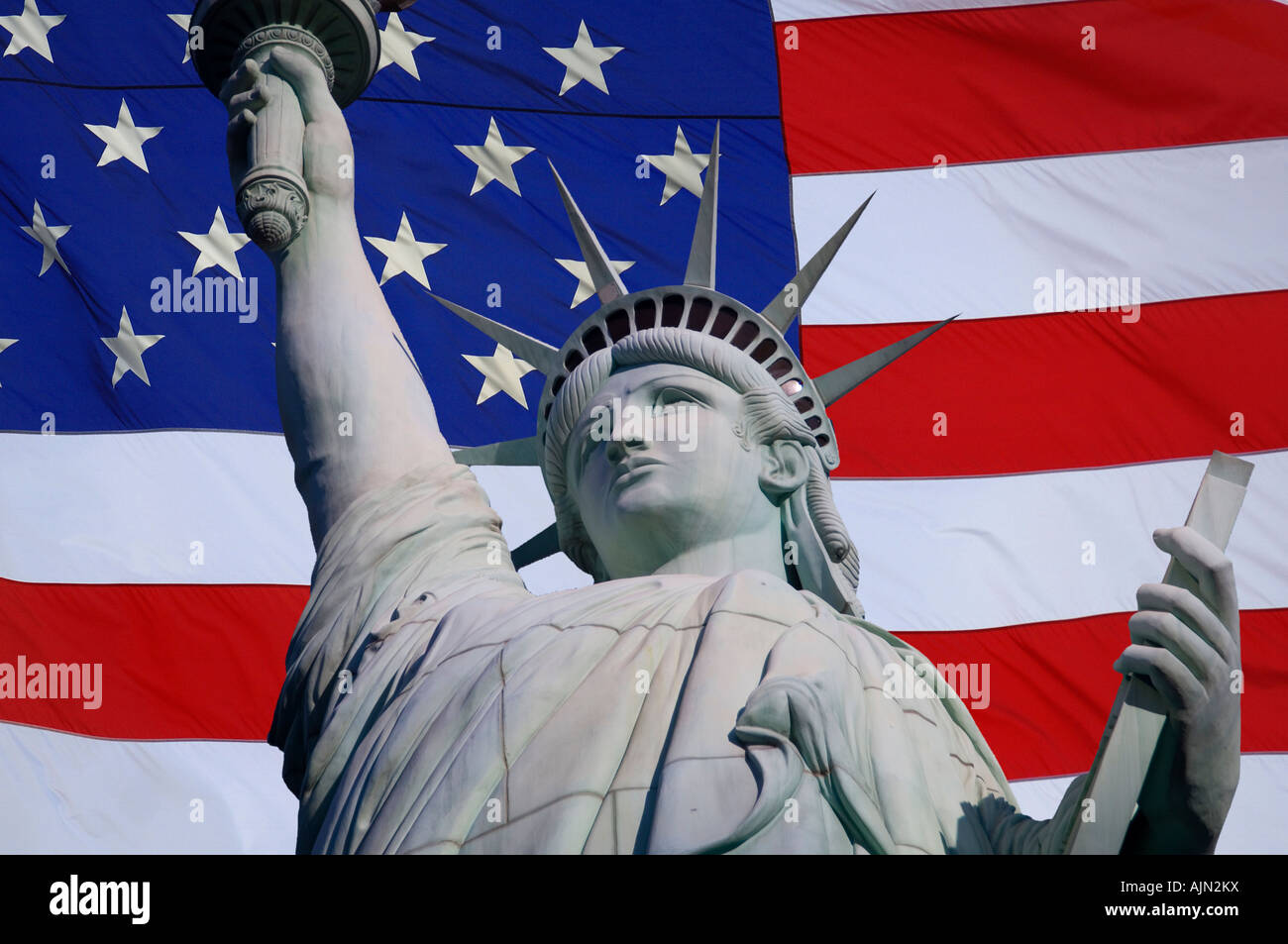 statue of liberty looking up with american stars and stripes flag in background behind Stock Photo