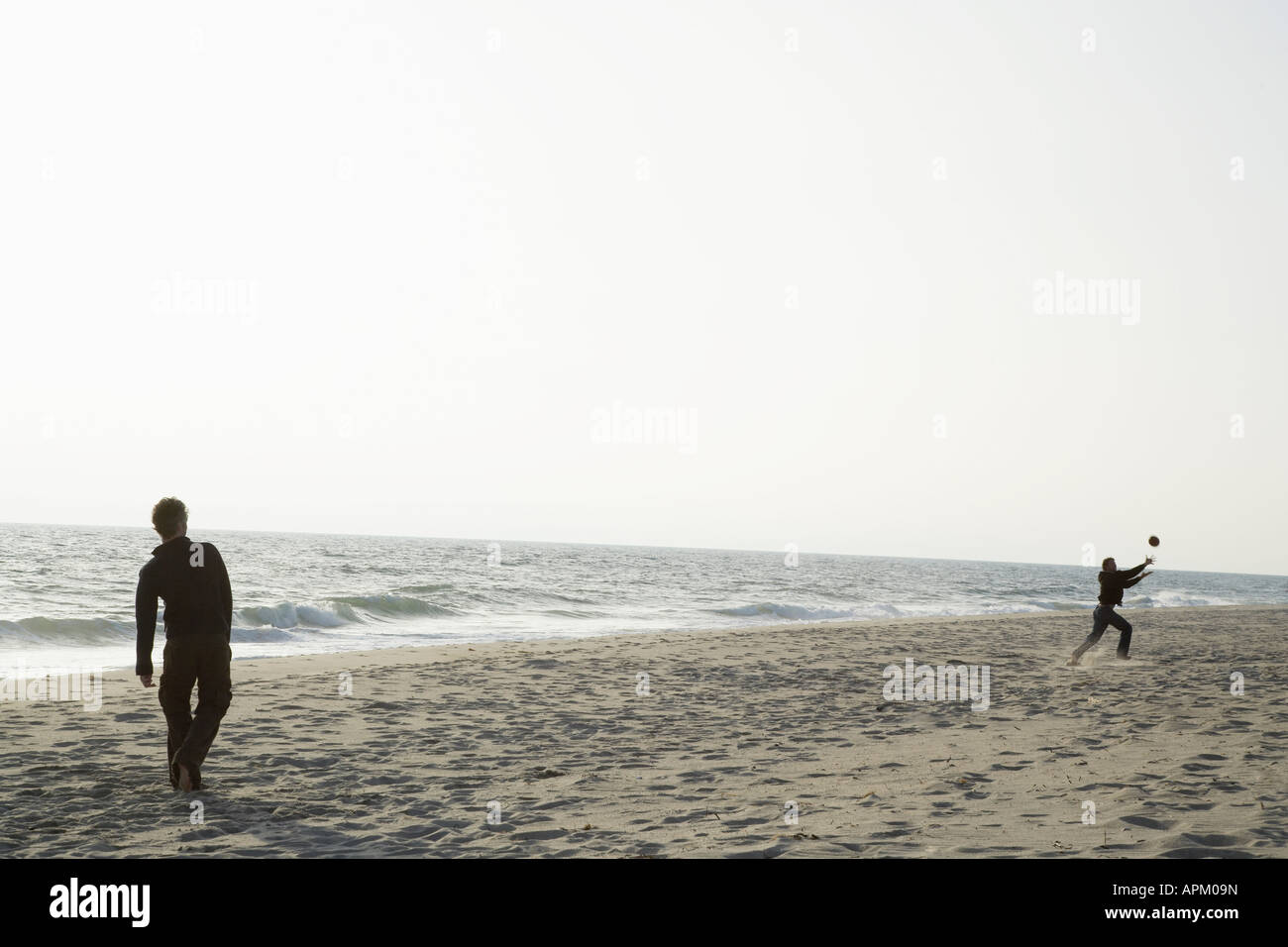 Two people throwing ball on beach Stock Photo