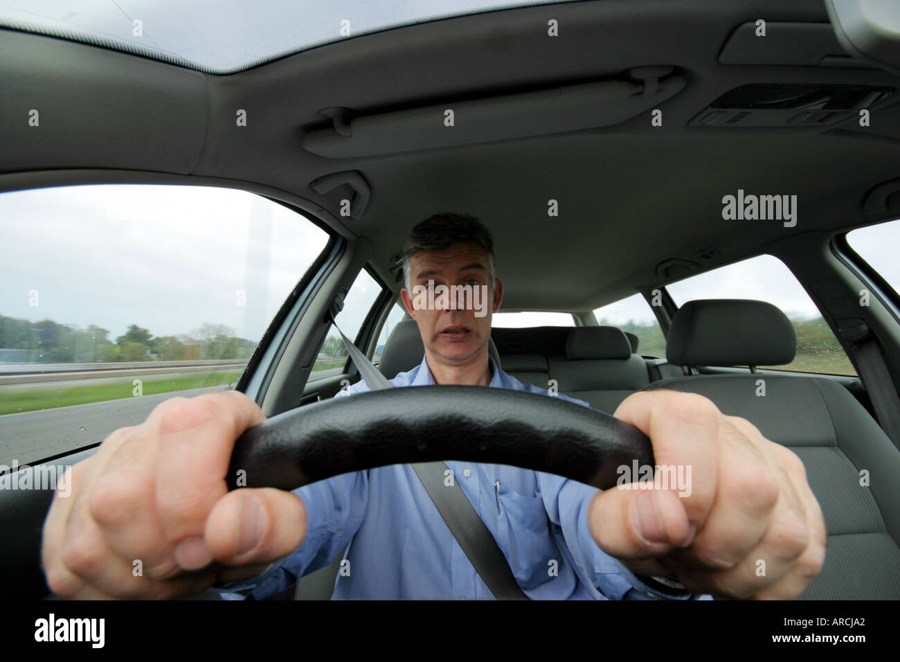 Front view of a man driving a car along UK motorway Stock Photo