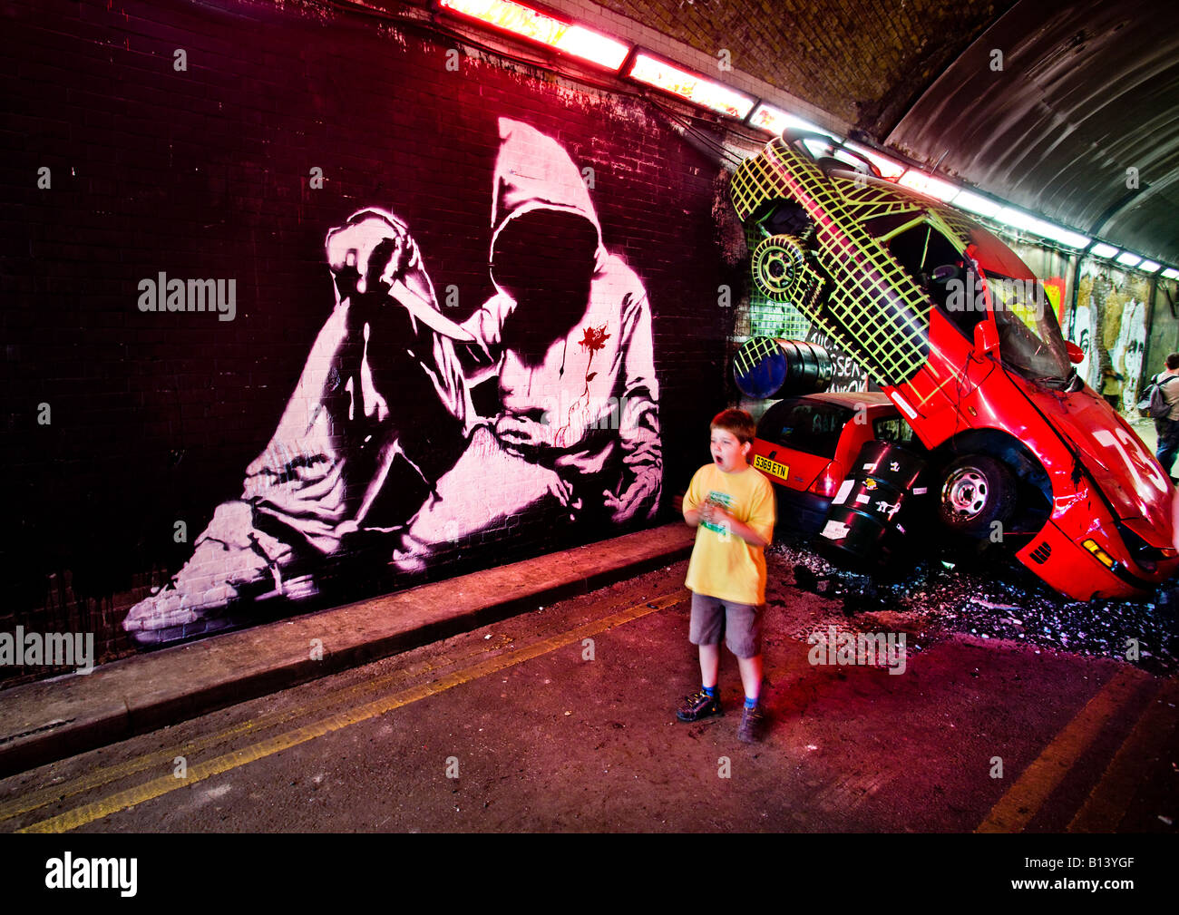 Dying man in a hoody mural by banksy in front of crashed cars at the Cans Festival Murals by Stock Photo