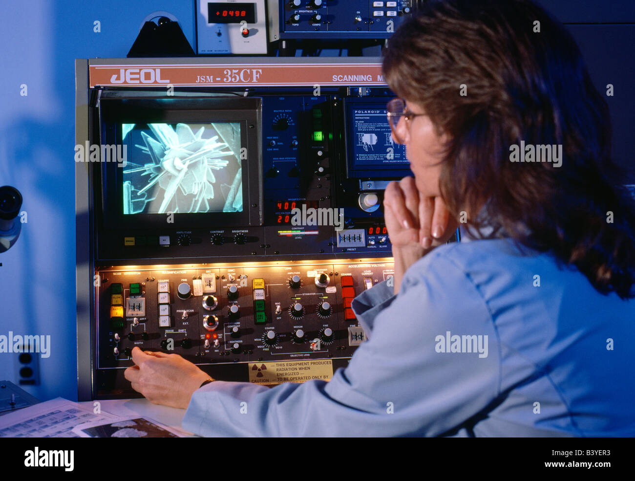 Female scientist uses scanning electron microscope to analyze materials Stock Photo