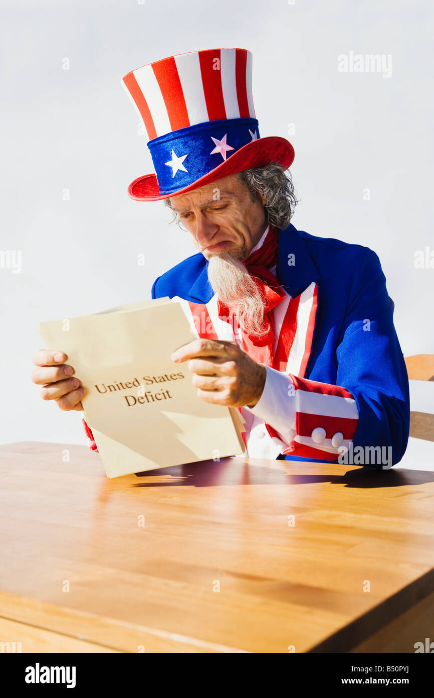 Uncle Sam sitting at a table looking at the United States Deficit Stock Photo