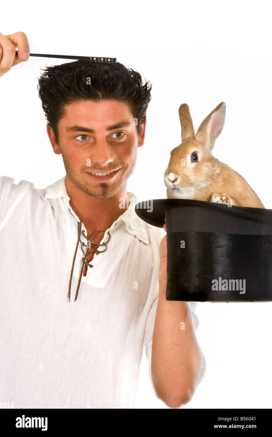 Young magician holding his magic wand over a rabbit in a top hat Stock Photo