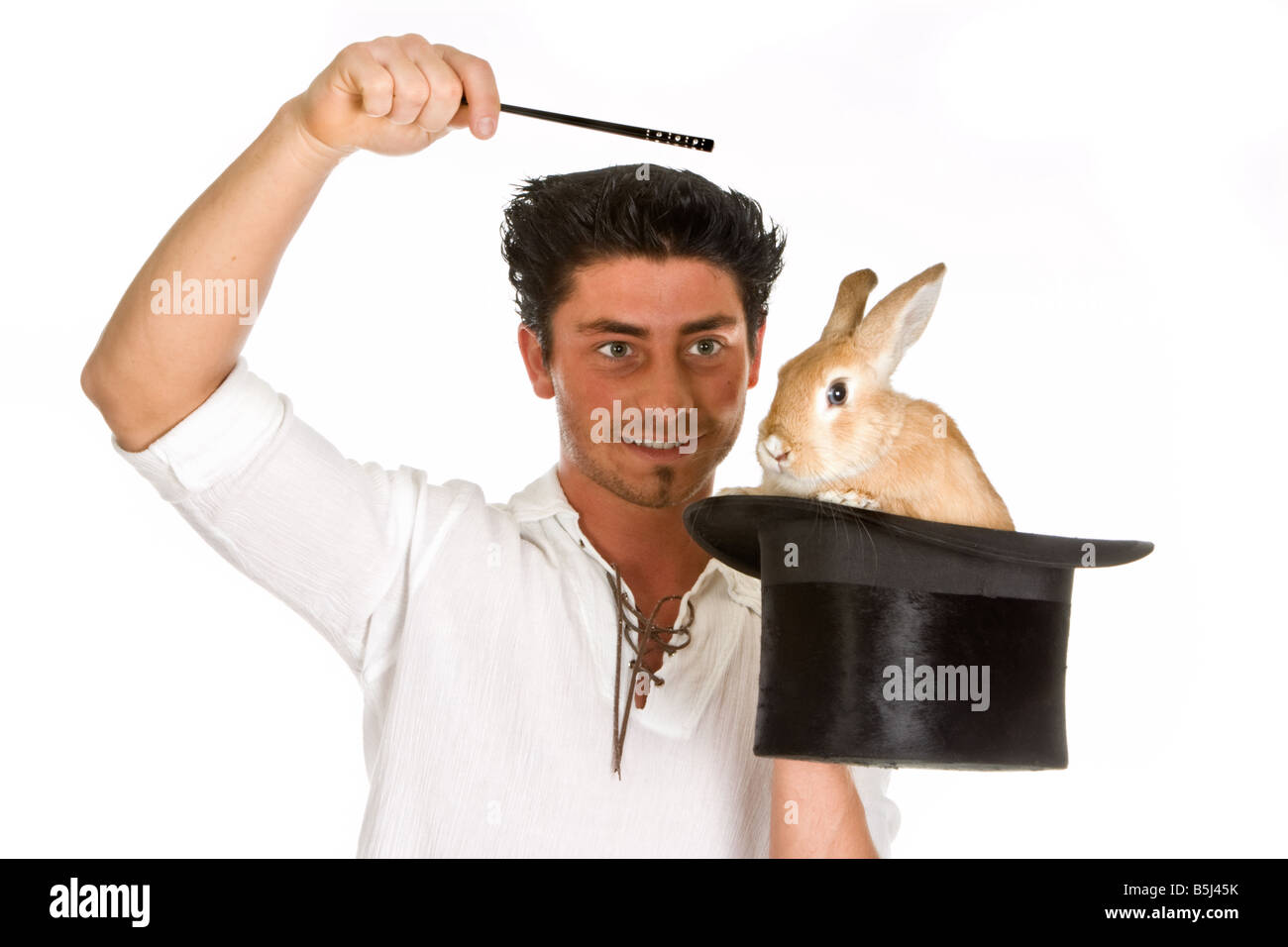 Young magician holding a magic wand above a rabbit in a top hat Stock Photo