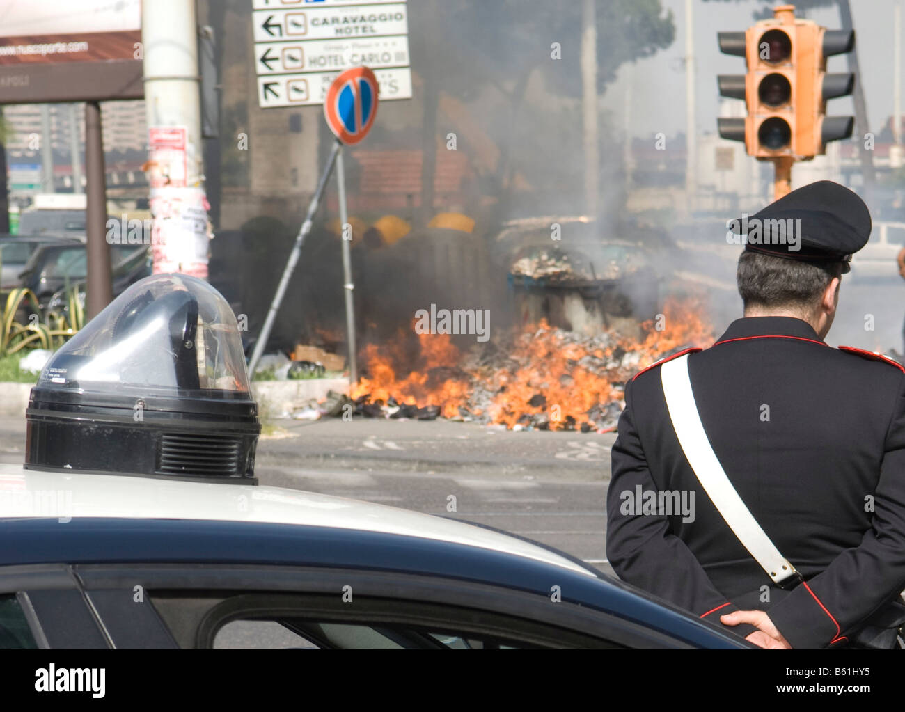 Household garbage catches fire in the summer heat, sometimes spontaneously, observed by a police officer or Carabiniere, Naples Stock Photo