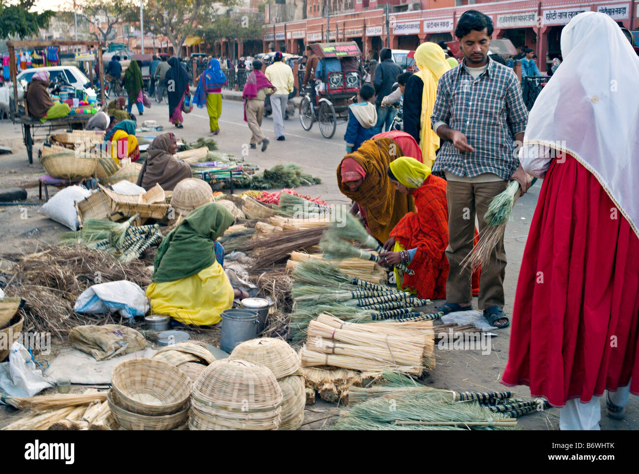 INDIA JAIPUR RAJASTHAN Indian women in colorful saris selling handmade brooms and baskets on the street in the market Stock Photo