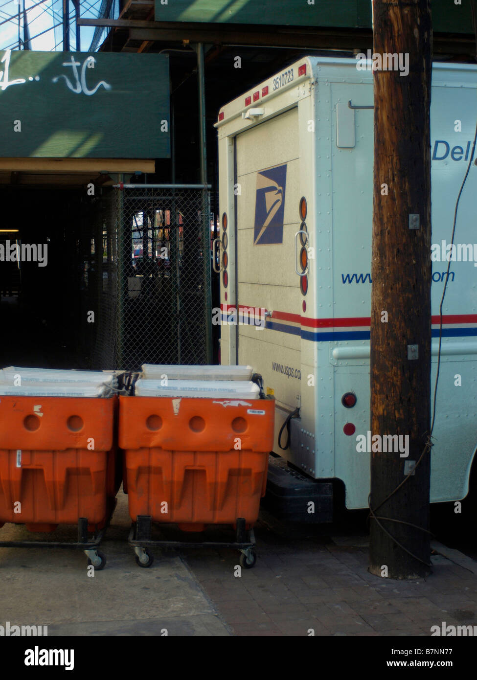 Full orange mail bins lined up and waiting to be loaded onto a USPS mail truck in New York City. Stock Photo