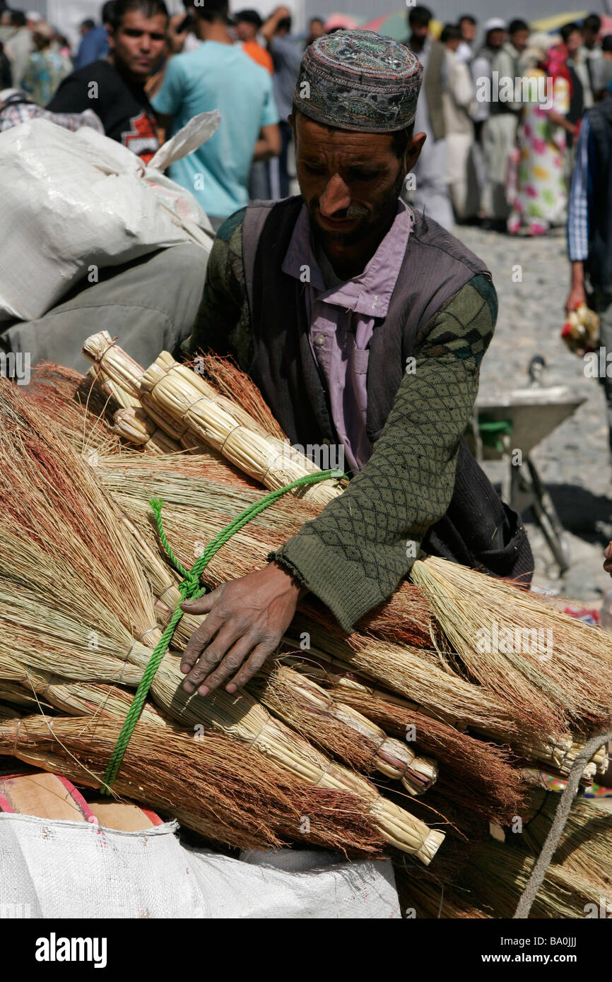 Afghan man selling hand-made brooms, transborder market near Ishkashim on the border between Tajikistan and Afghanistan Stock Photo