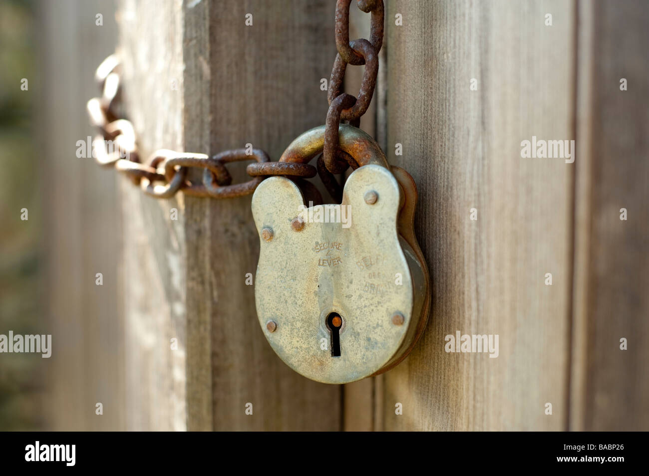 A rusted padlock and chain against a brown door Stock Photo