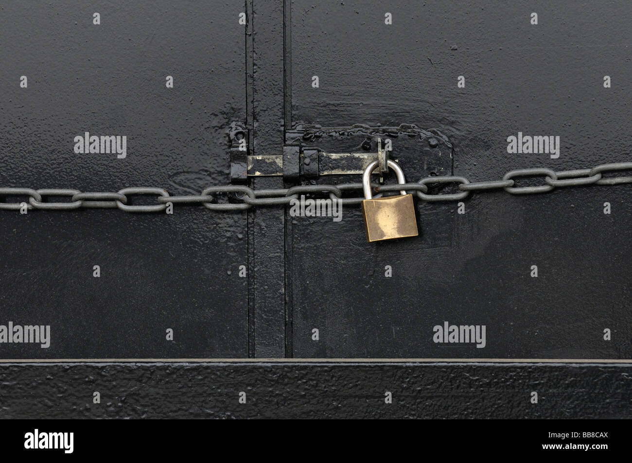 Metal door secured by bar with padlock and chain Stock Photo