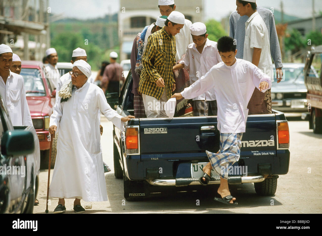 Thailand, Worshippers dress in traditional garb arrive for Friday prayers in the back of a pickup truck. Stock Photo