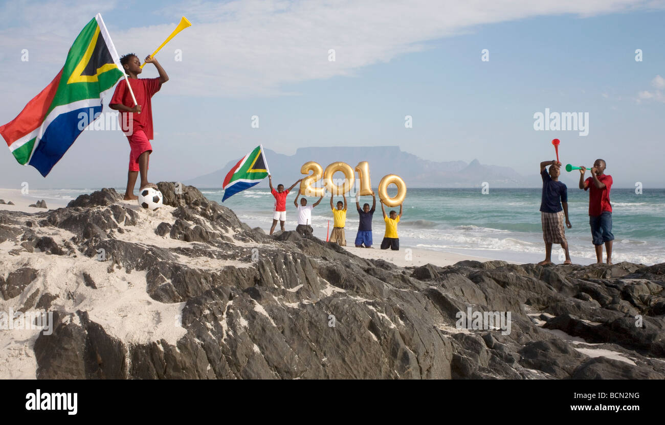 Group of boys on  beach blowing Vuvuzelas, and holding golden balloons shaped as numbers for 2010 , Blouberg Beach Stock Photo