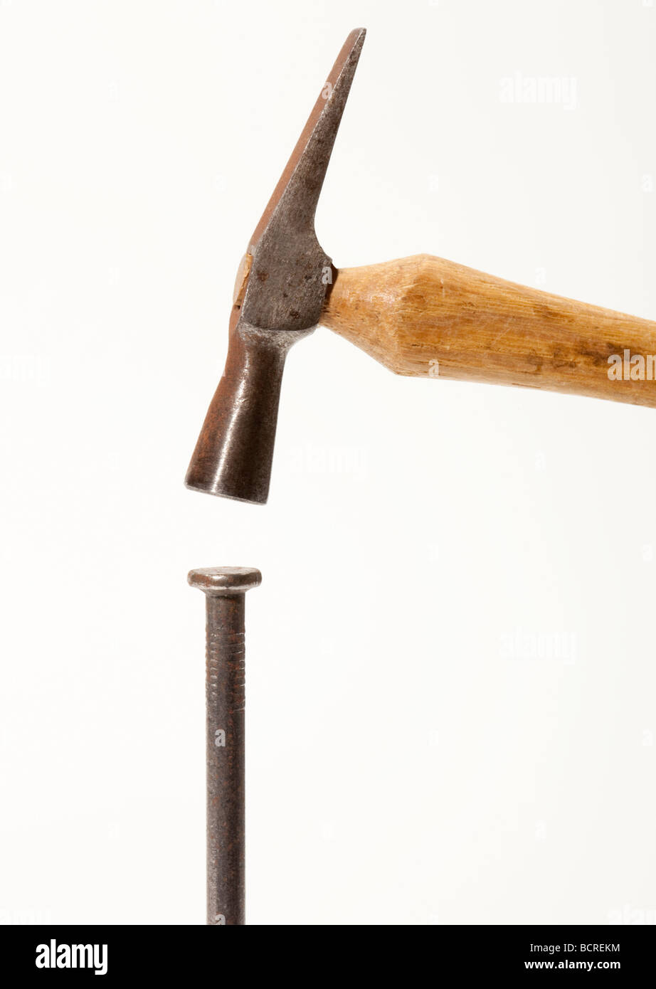 A small hammer about to hit a large nail Stock Photo