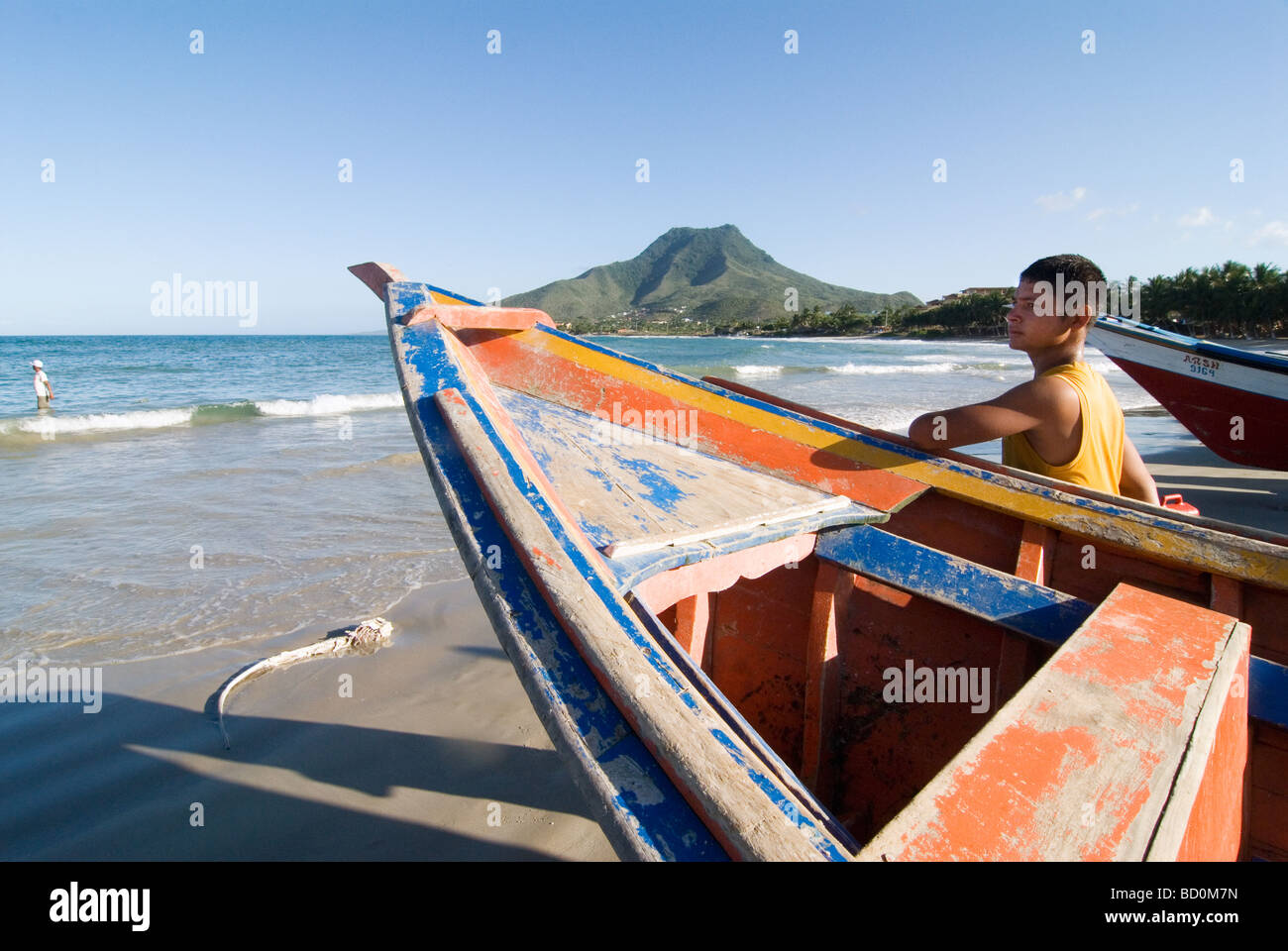 Boy beneath a fisherboat on the island Isla de Margarita, Venezuela. Stock Photo