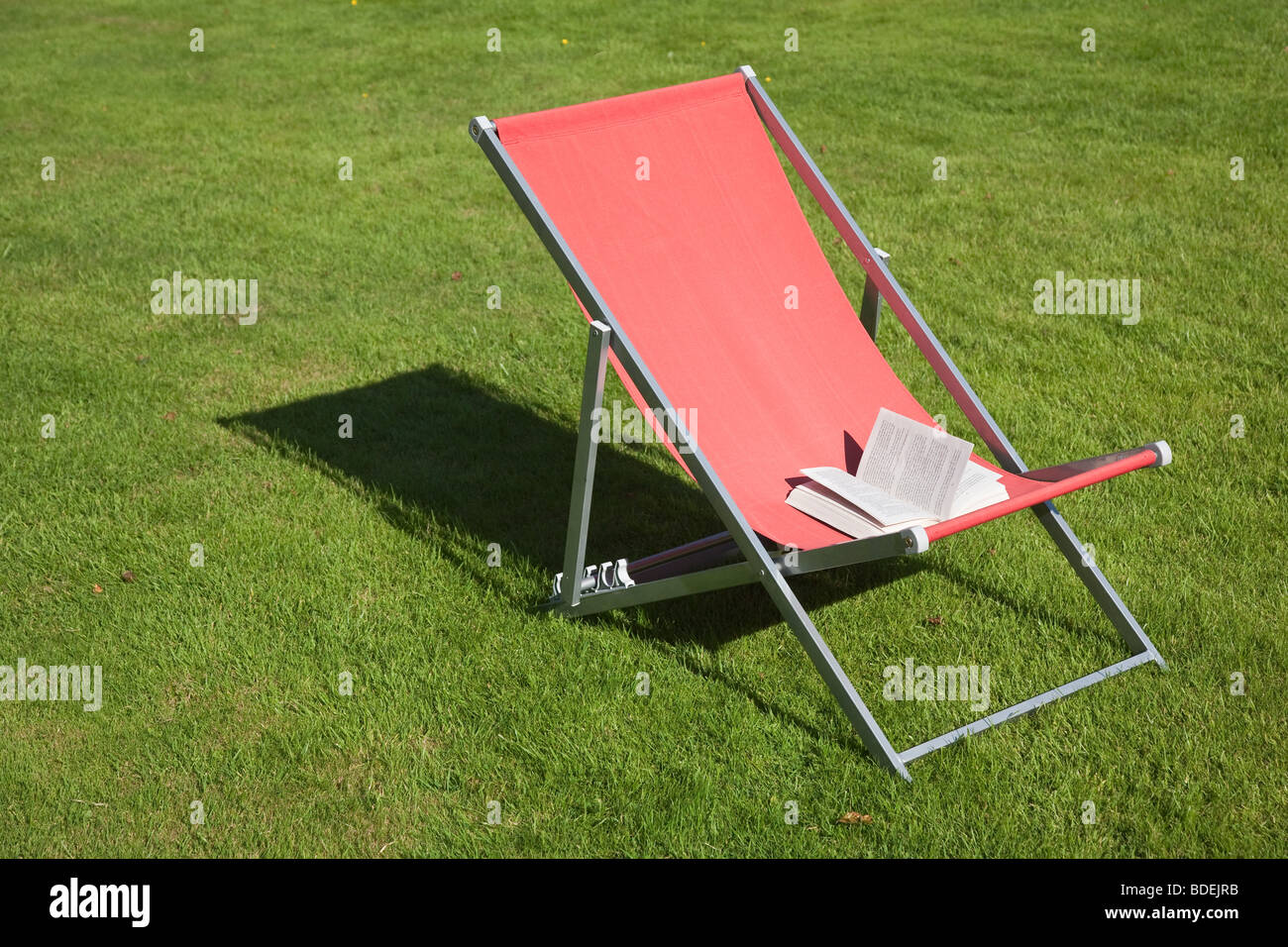 open paperback book on red deckchair Stock Photo