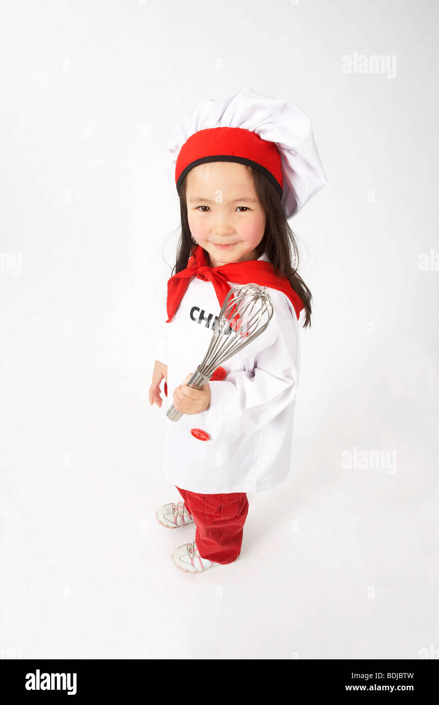 Little Girl Dressed Up as a Chef Holding a Whisk Stock Photo