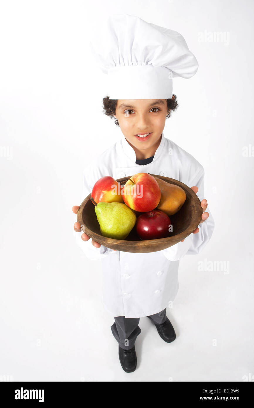 Boy Dressed Up as a Chef Holding Bowl of Fruit Stock Photo