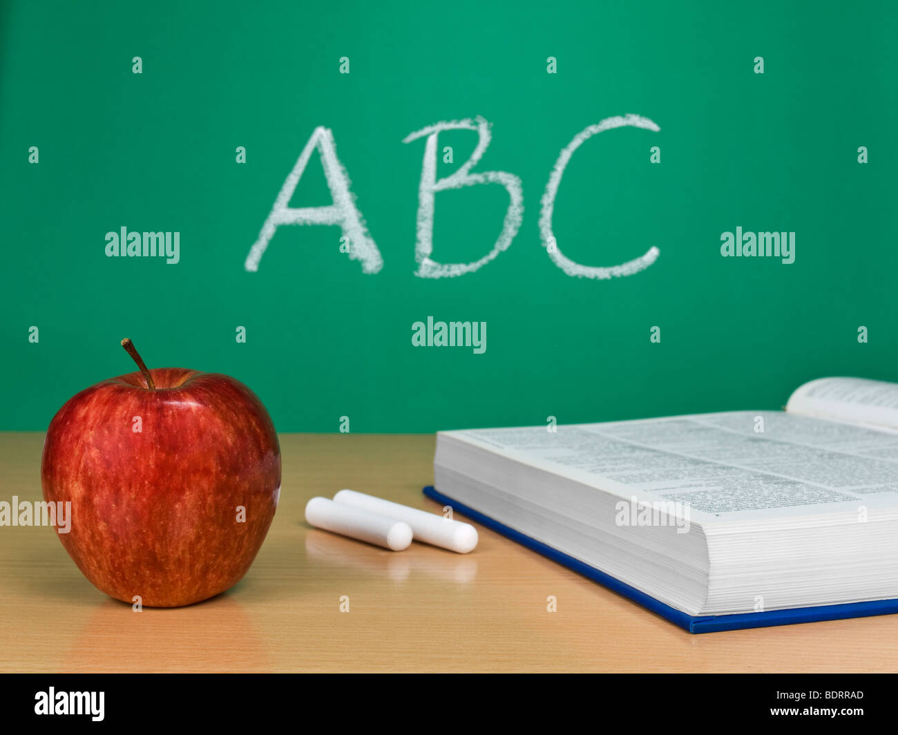 ABC written on a chalkboard with an apple, a book and some chalks. Stock Photo