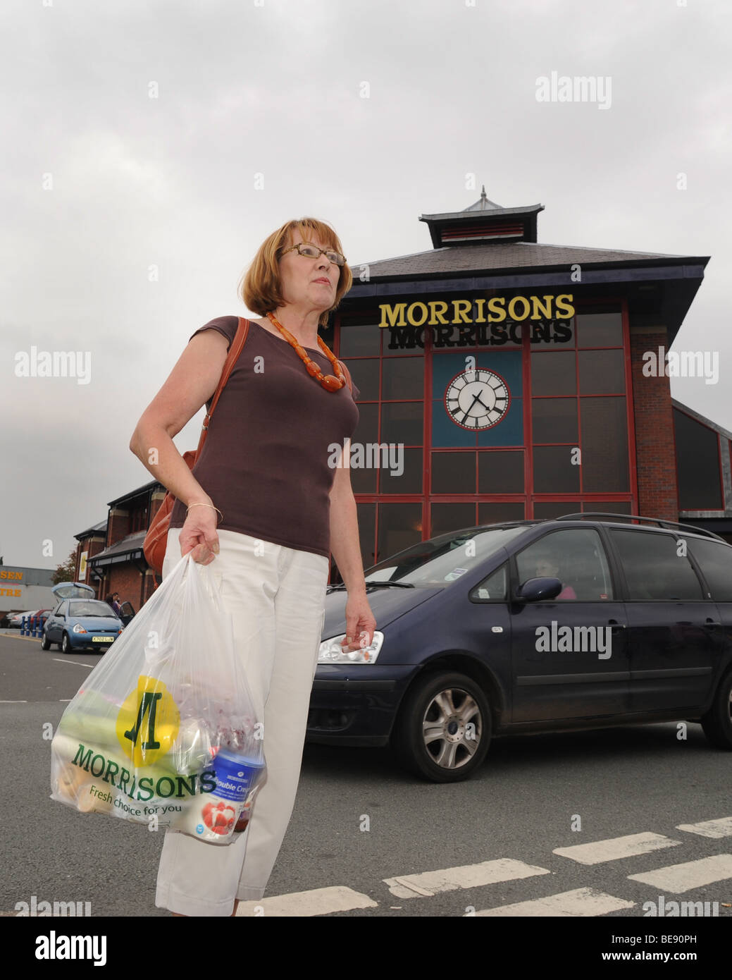 Middle aged woman shopper leaving Morrisons supermarket Wellington Shropshire England Uk Stock Photo