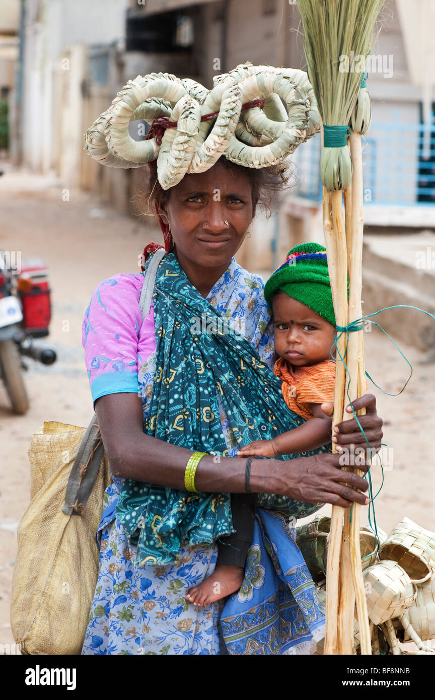 Indian mother and baby selling handmade brushes and baskets with pot stands on her head. Puttaparthi, Andhra Pradesh, India Stock Photo