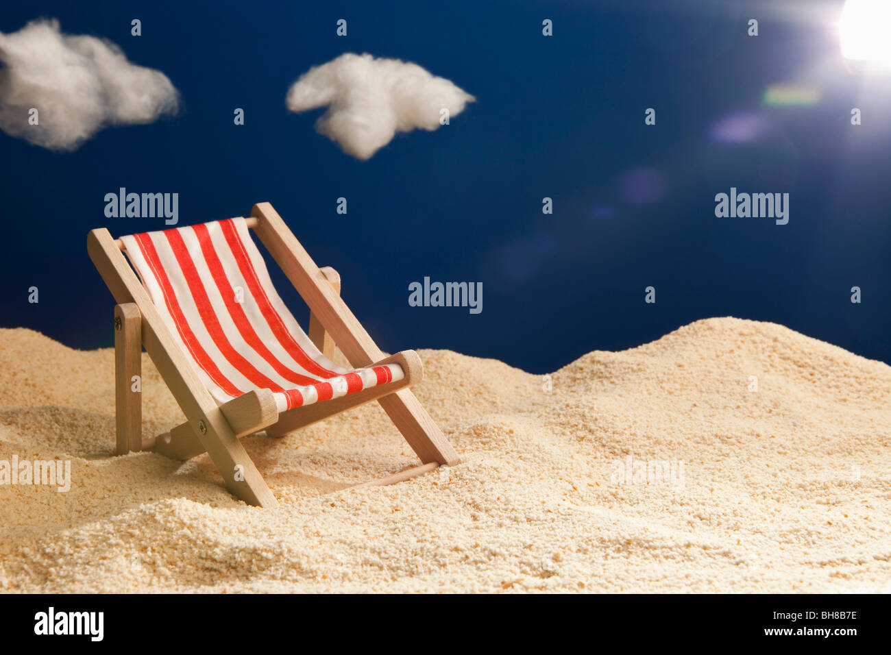 A miniature beach chair in sand Stock Photo