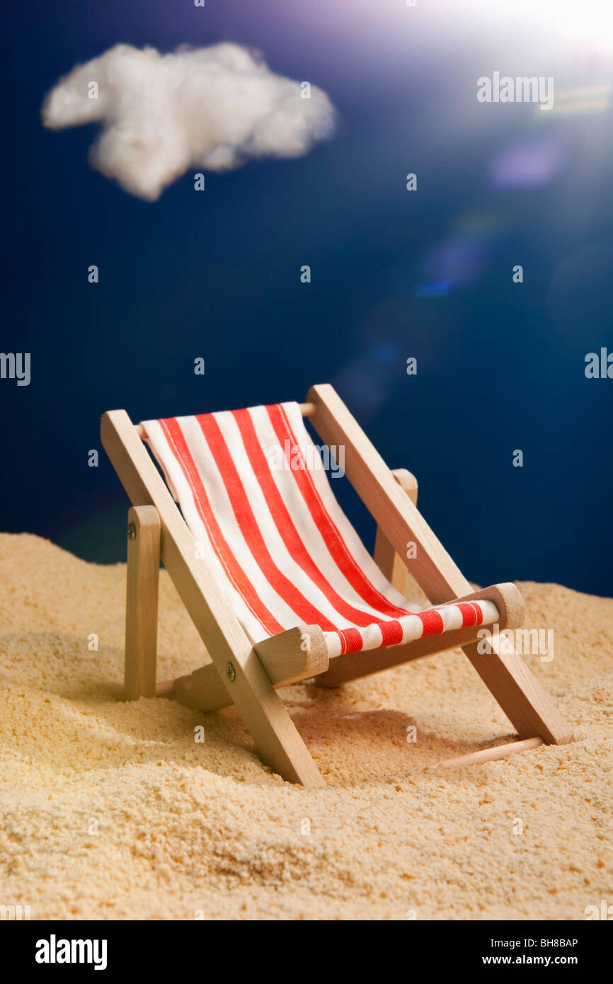 A miniature beach chair in sand Stock Photo