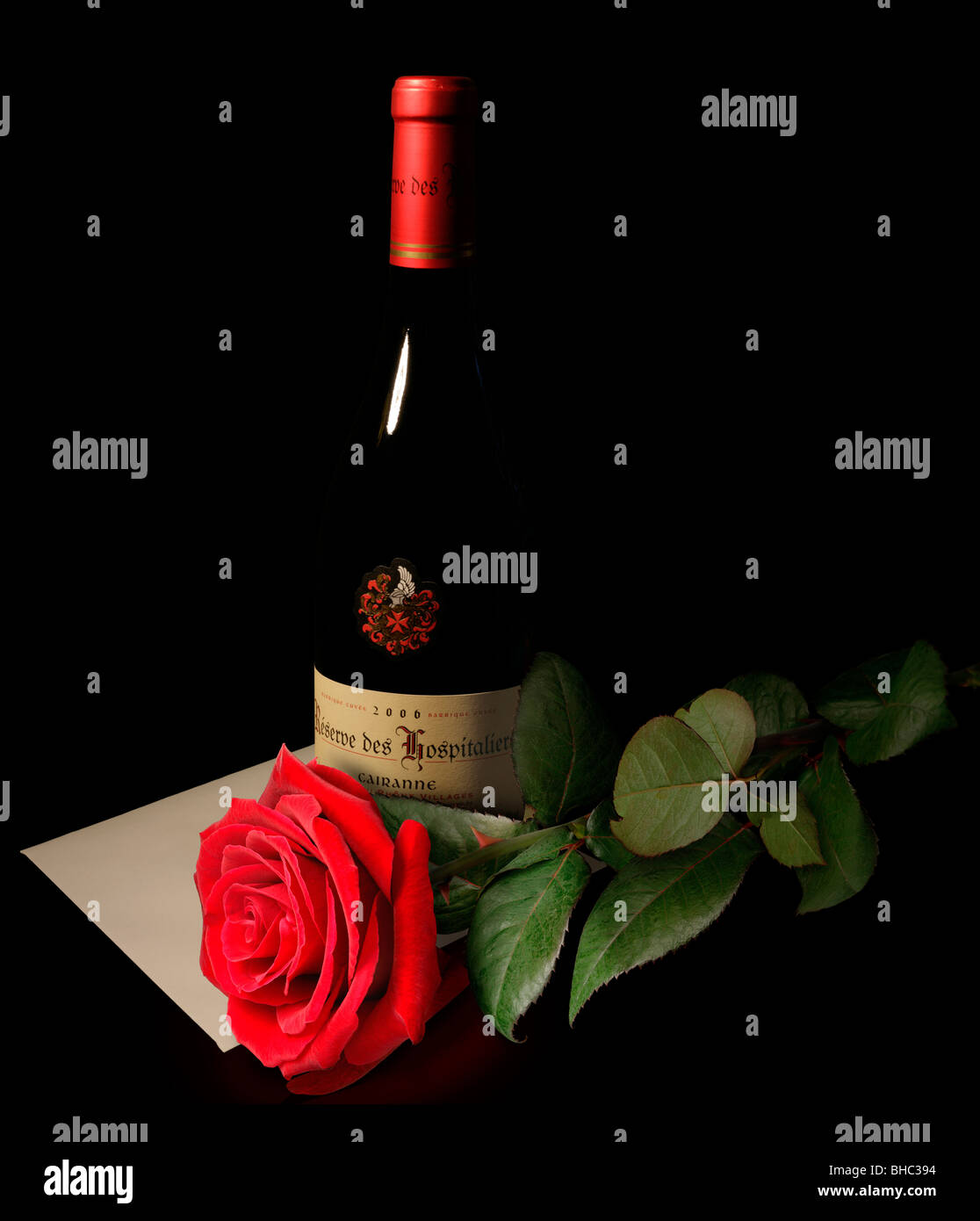 red rose with a card and a bottle of wine on black background Stock Photo