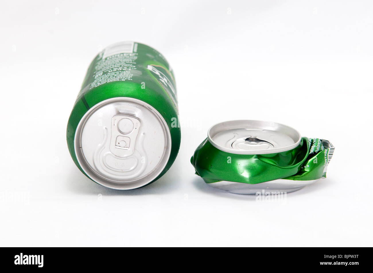 Beer can laying next to crushed beer can Stock Photo