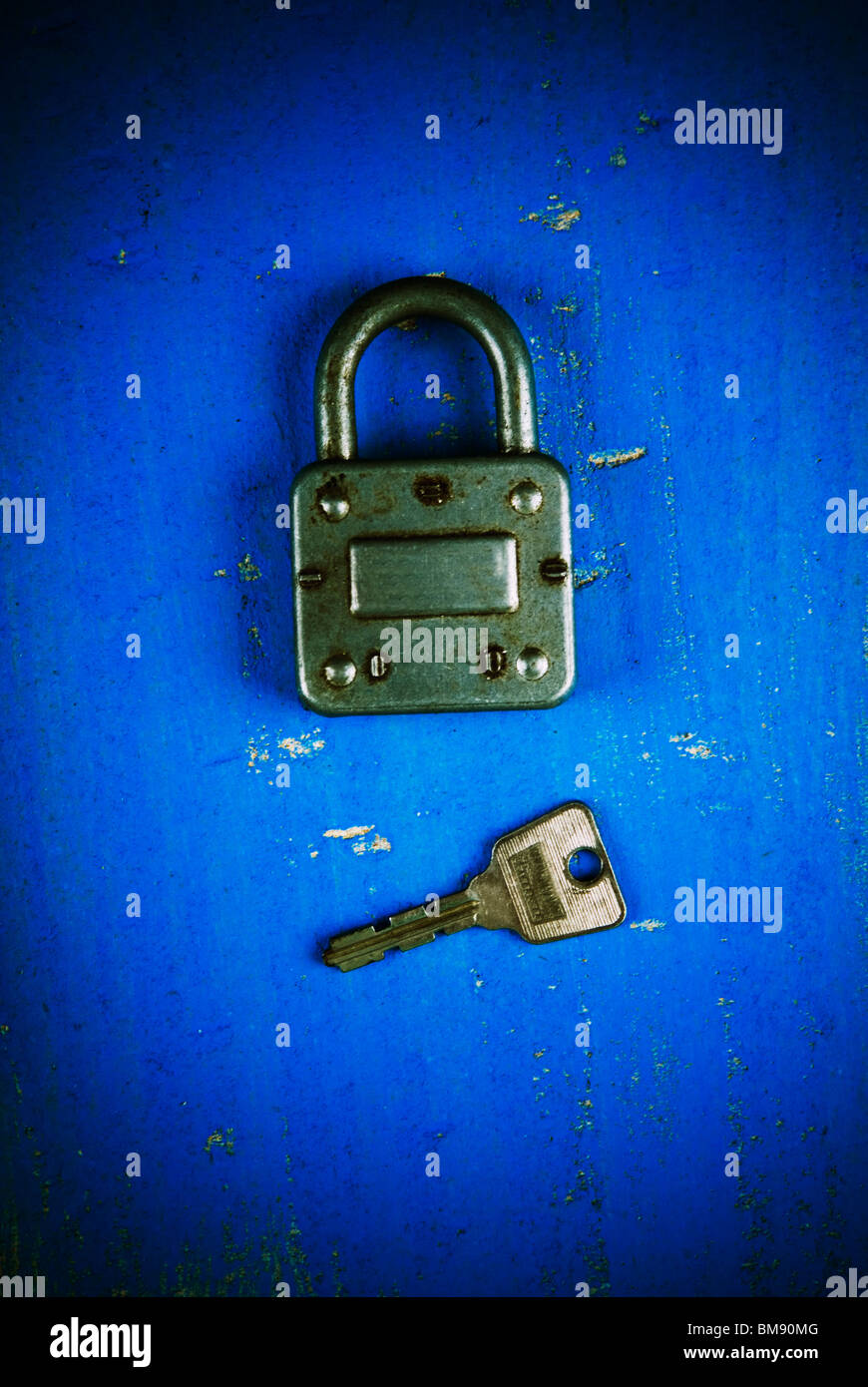 Old fashioned padlock with key on a blue wooden background Stock Photo