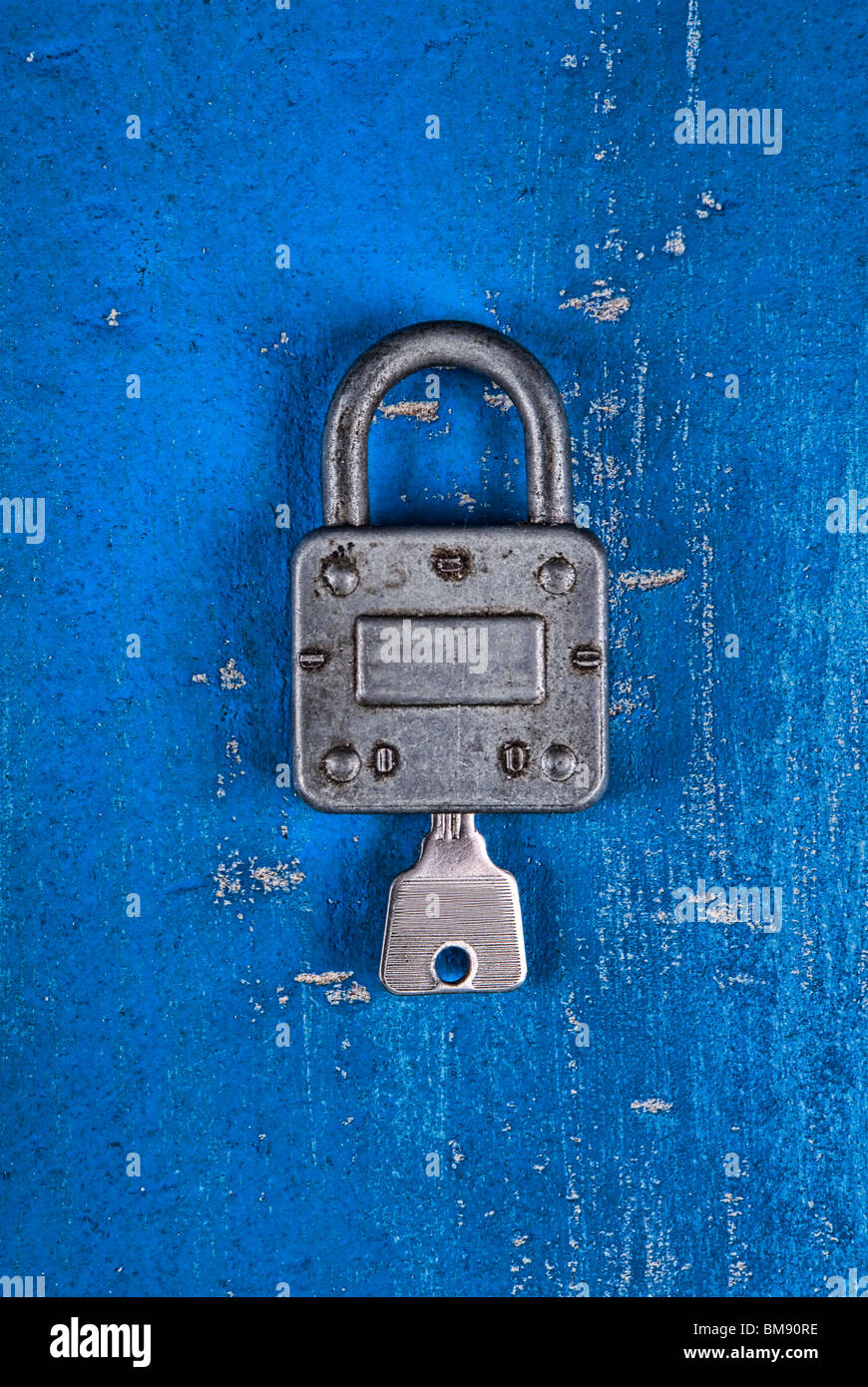 Old fashioned padlock with key on a blue wooden background Stock Photo