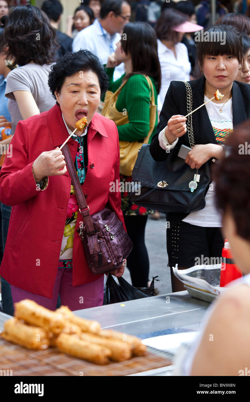 Woman eating fish cake on a stick in Seoul, South Korea Stock Photo