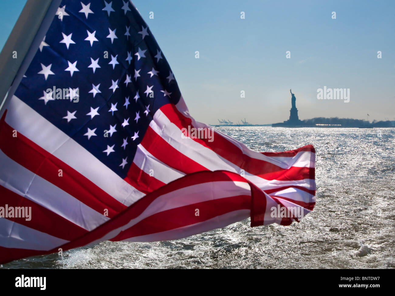 The American flag the Stars and Stripes with Statue of Liberty in background, New York, USA. America Stock Photo