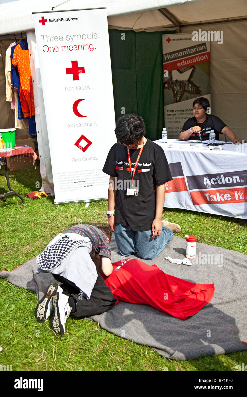 Young volunteer at the British Red Cross stand at Edinburgh Mela 2010 instructing a boy in artificial respiration technique. Stock Photo