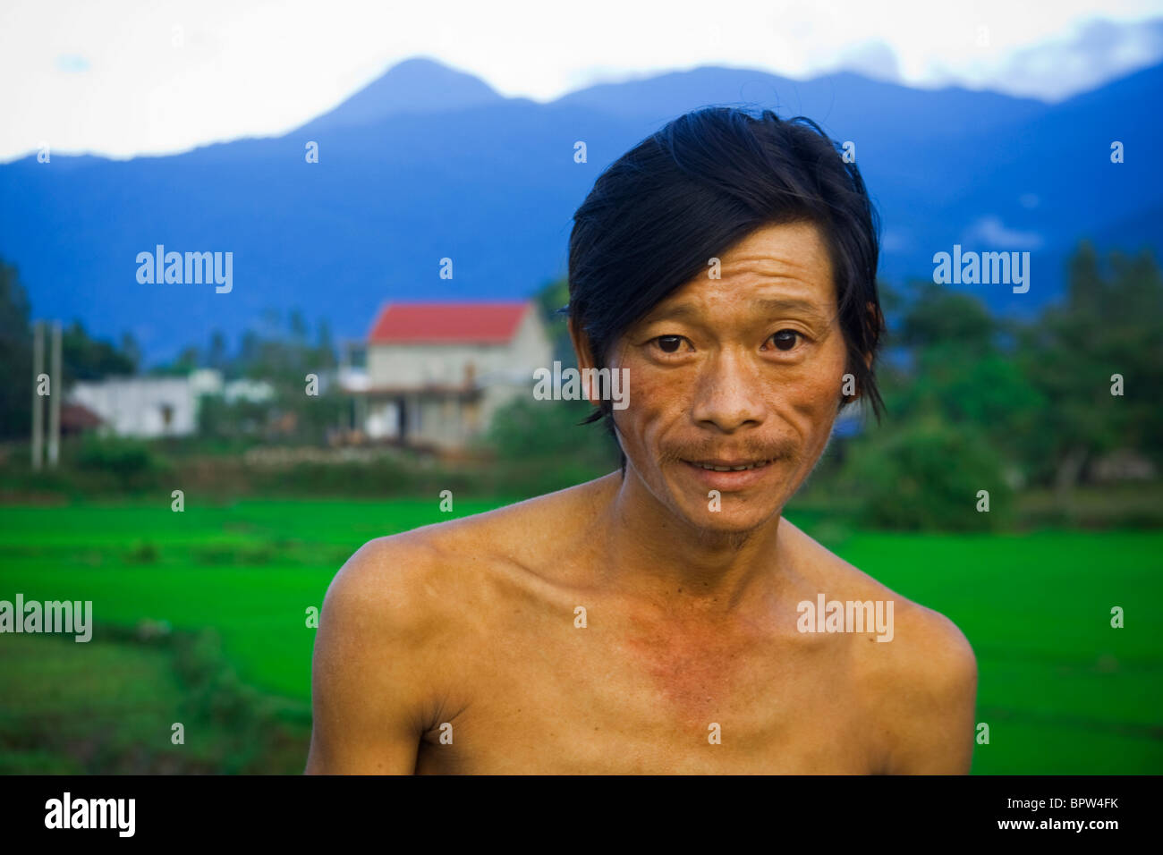 Portrait of Vietnamese Farmer in front of rice paddies, Central Vietnam. Indochina. Southeast Asia. January 2010. Stock Photo