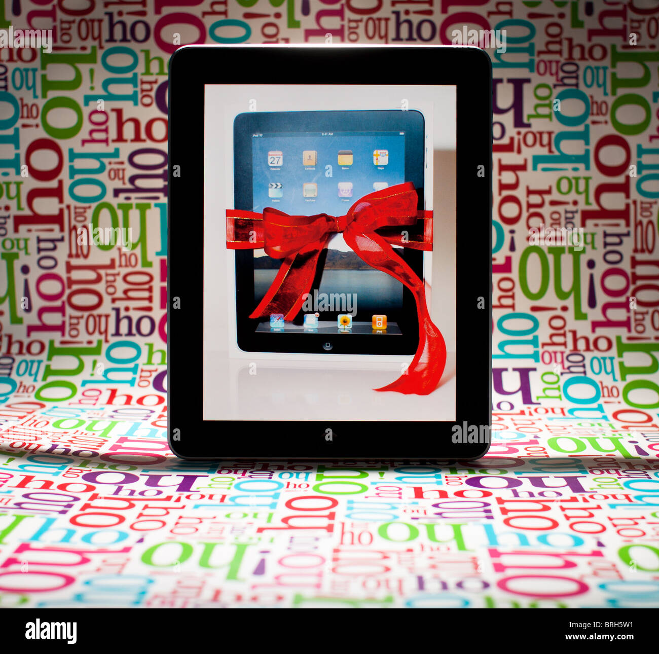 A photo of a gift-wrapped iPad on the screen of an iPad (with 'Ho Ho Ho' wrapping paper background). Stock Photo