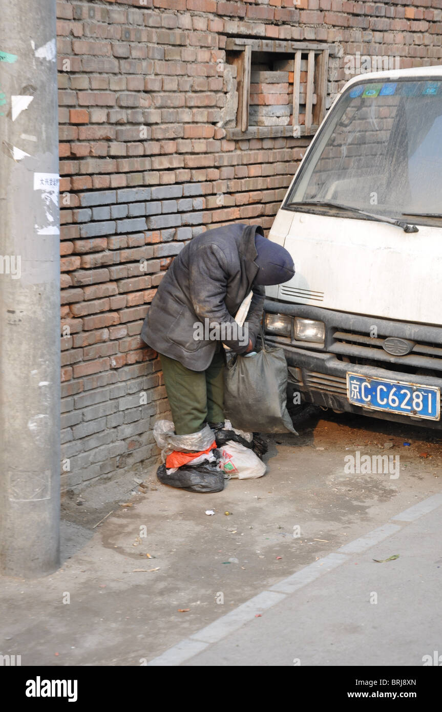 Poor man standing while sleeping in a Beijing hutong, China Stock Photo