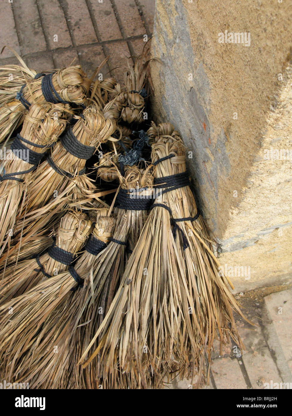 A display of handmade straw brooms for sale in the market in Essaouira, Morocco Stock Photo