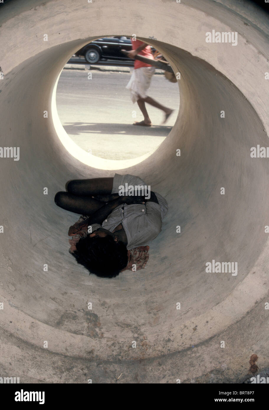 Homeless man sleeping in a pipe in Mumbai India Stock Photo