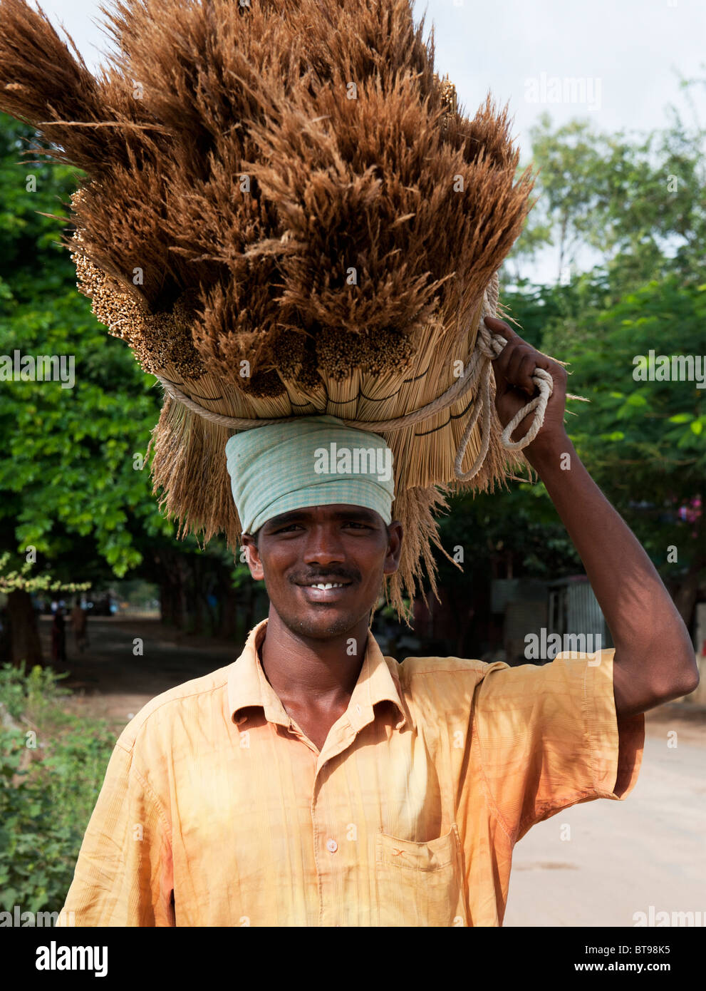 Indian man selling handmade brushes that are balancing on his head.  Andhra Pradesh, India Stock Photo