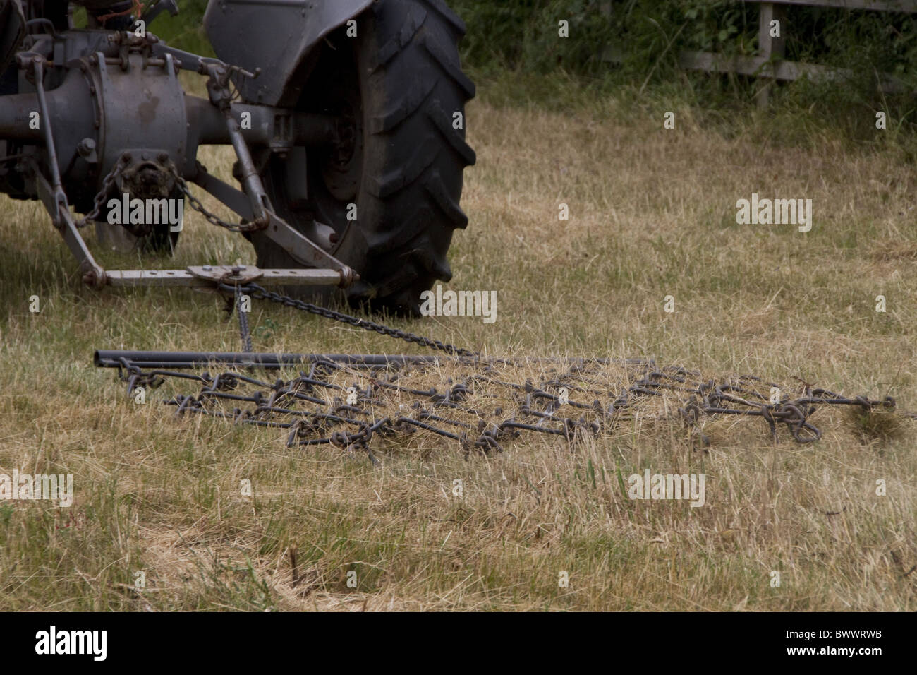 Old grey fergie pulling chain harrow Stock Photo