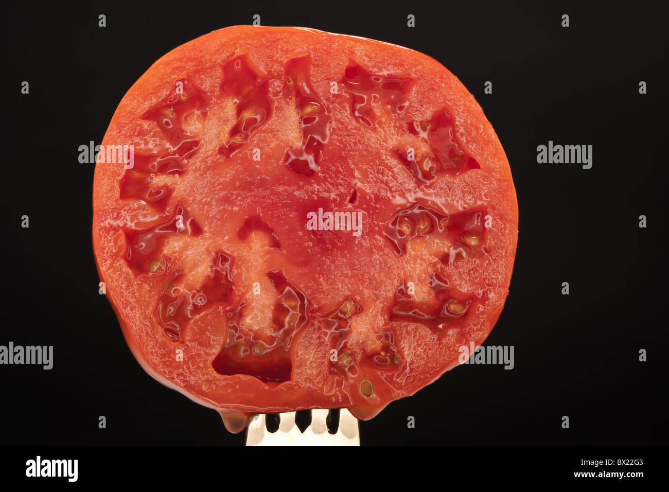 A cut, juicy, tomato is laid on a black background Stock Photo