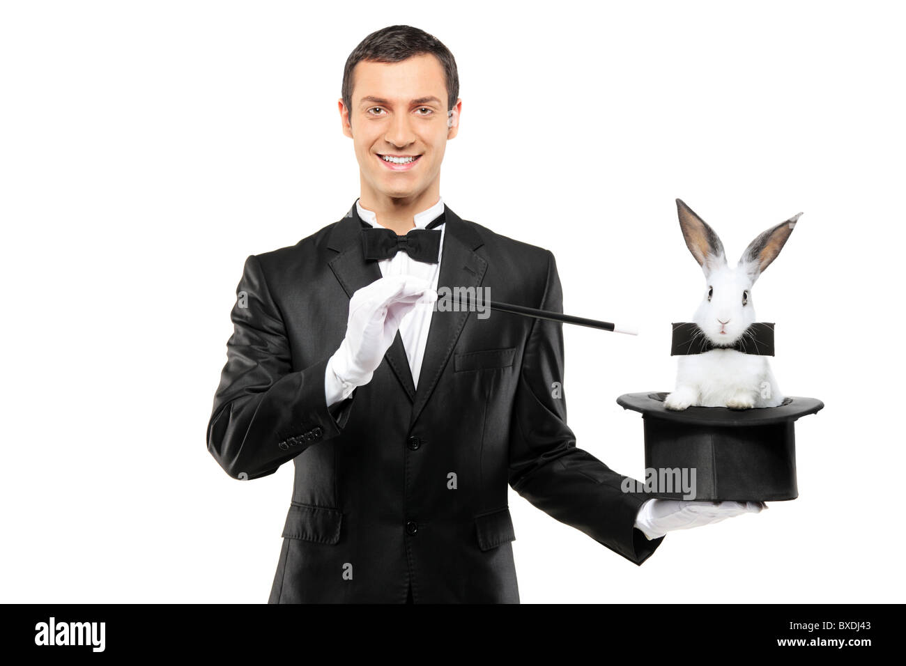 A magician in a black suit holding a top hat with a rabbit in it Stock Photo