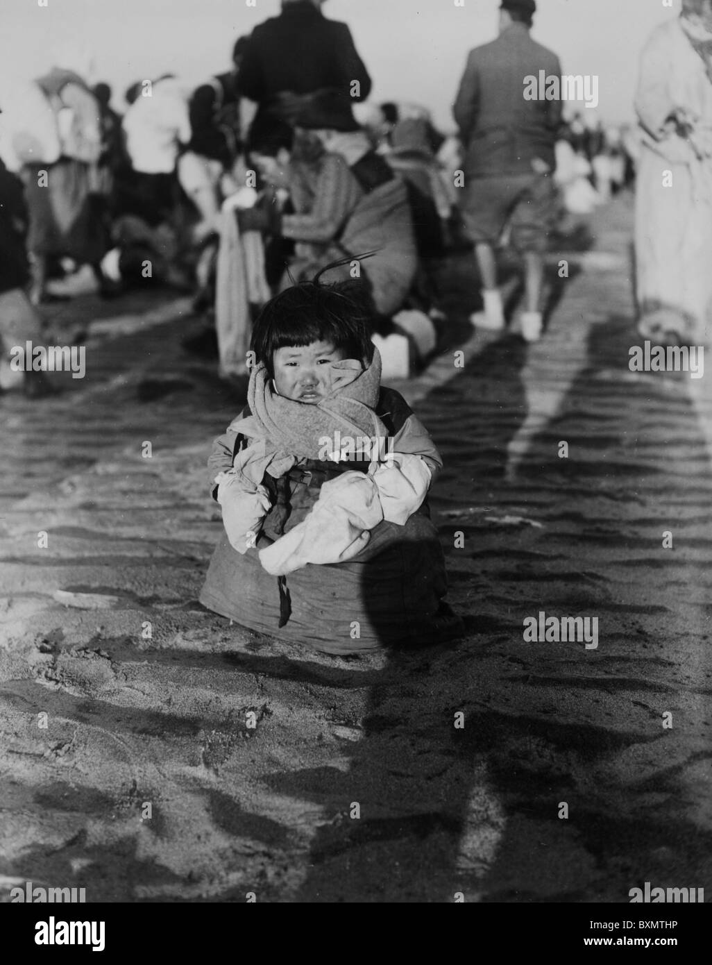 A small Korean child searches for her family as the Korean Refugees flee across the Taedong River a Pyongyang, North Korea Stock Photo