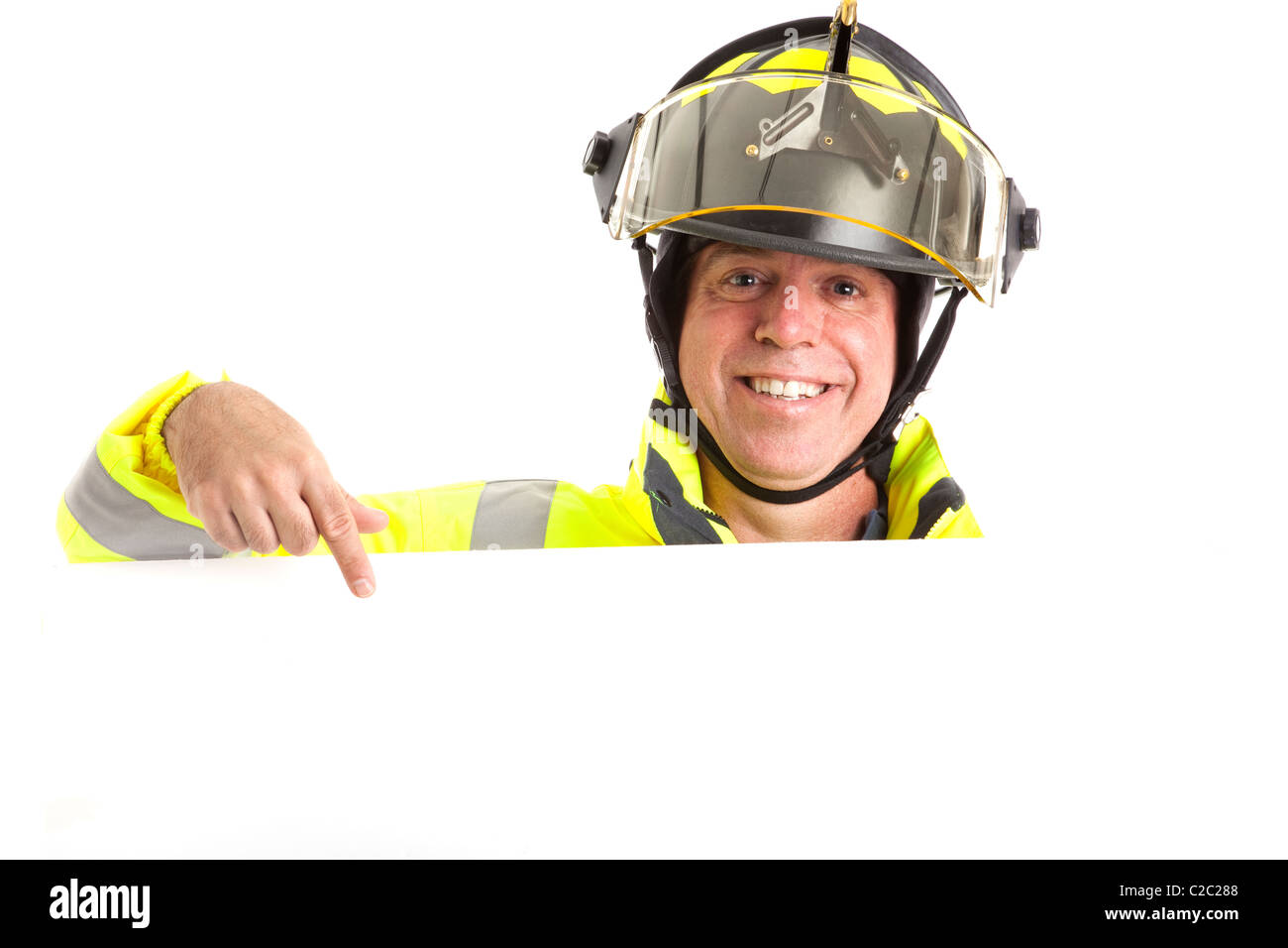 Friendly fireman in uniform, pointing to blank white space, ready for your message. Stock Photo