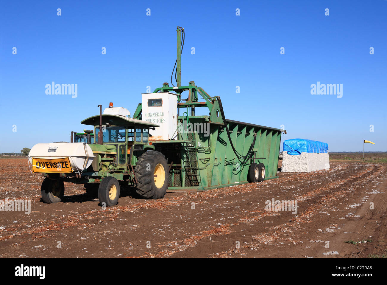 John Deere tractor attached to a cotton module builder, or compacting machine, with a completed cotton module. Stock Photo