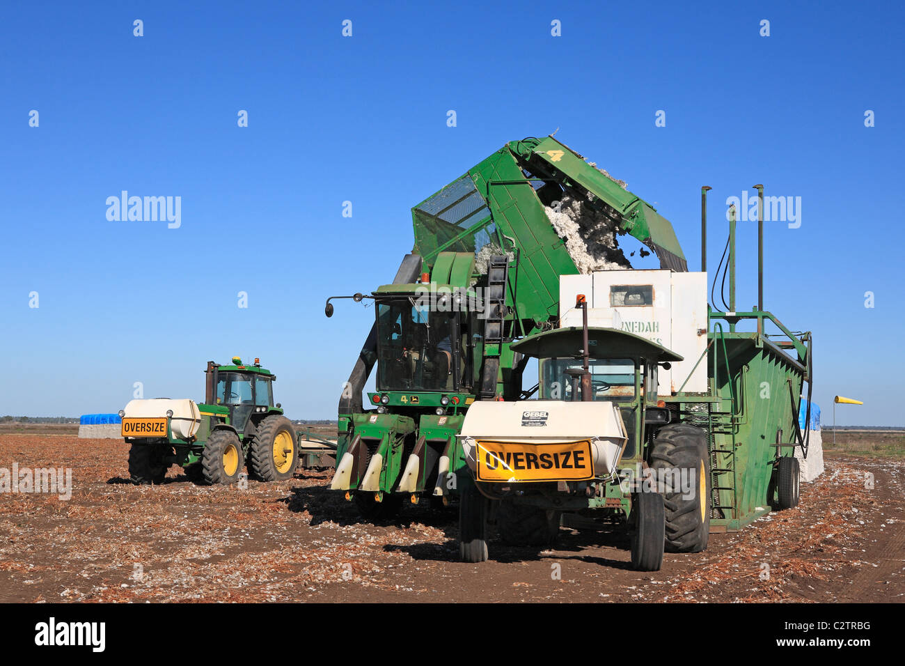 John Deere tractor attached to a cotton module builder, or compacting machine, with a completed cotton module. Stock Photo