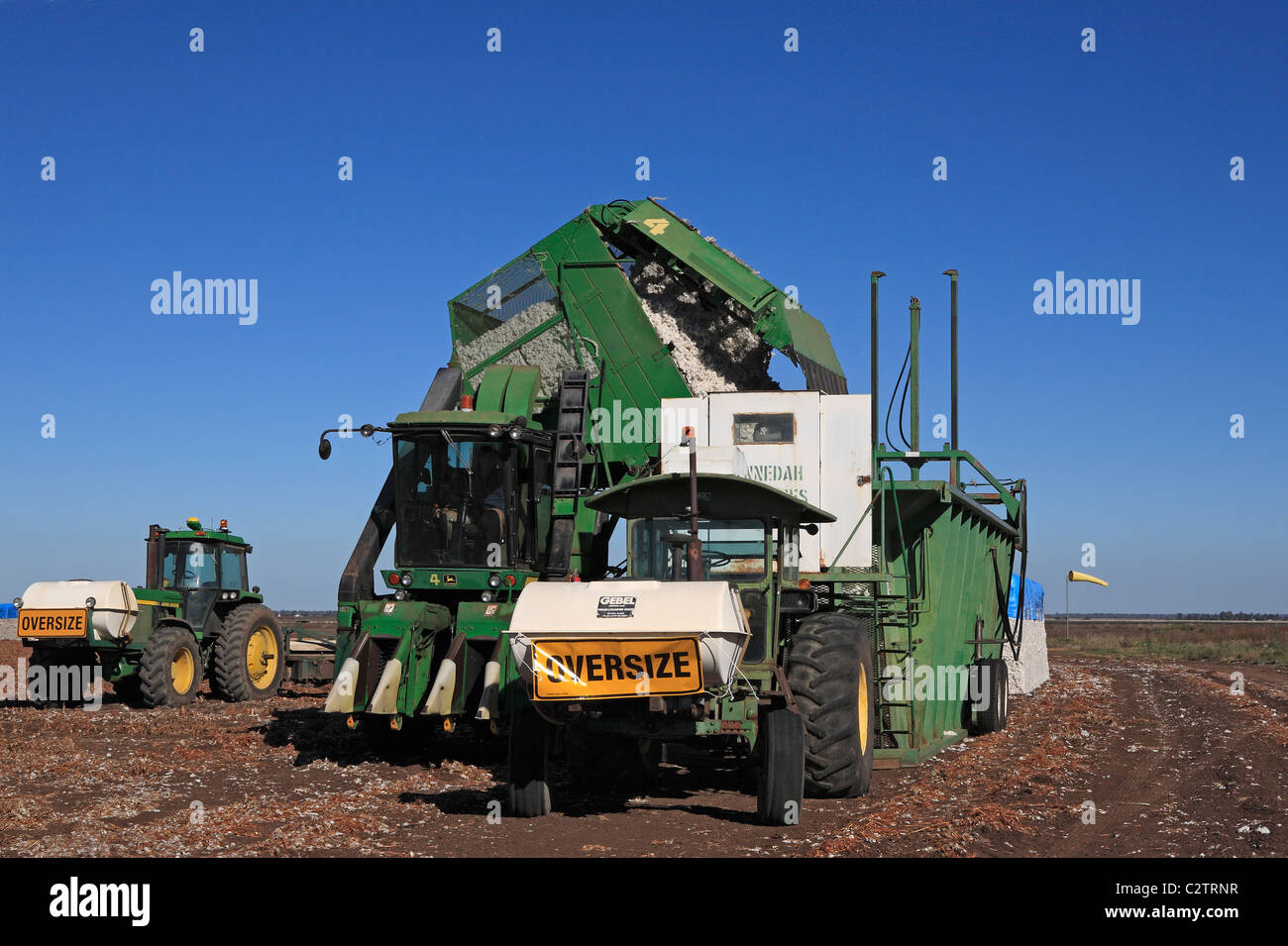 John Deere tractor attached to a cotton module builder, or compacting machine, with a completed cotton module Stock Photo