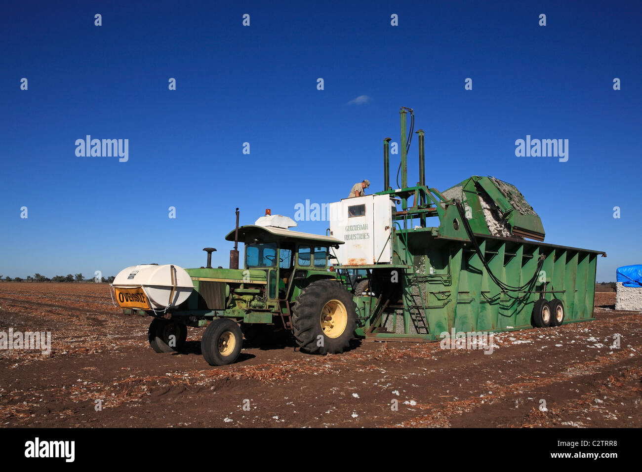 John Deere tractor attached to a cotton module builder, or compacting machine, with a completed cotton module. Stock Photo