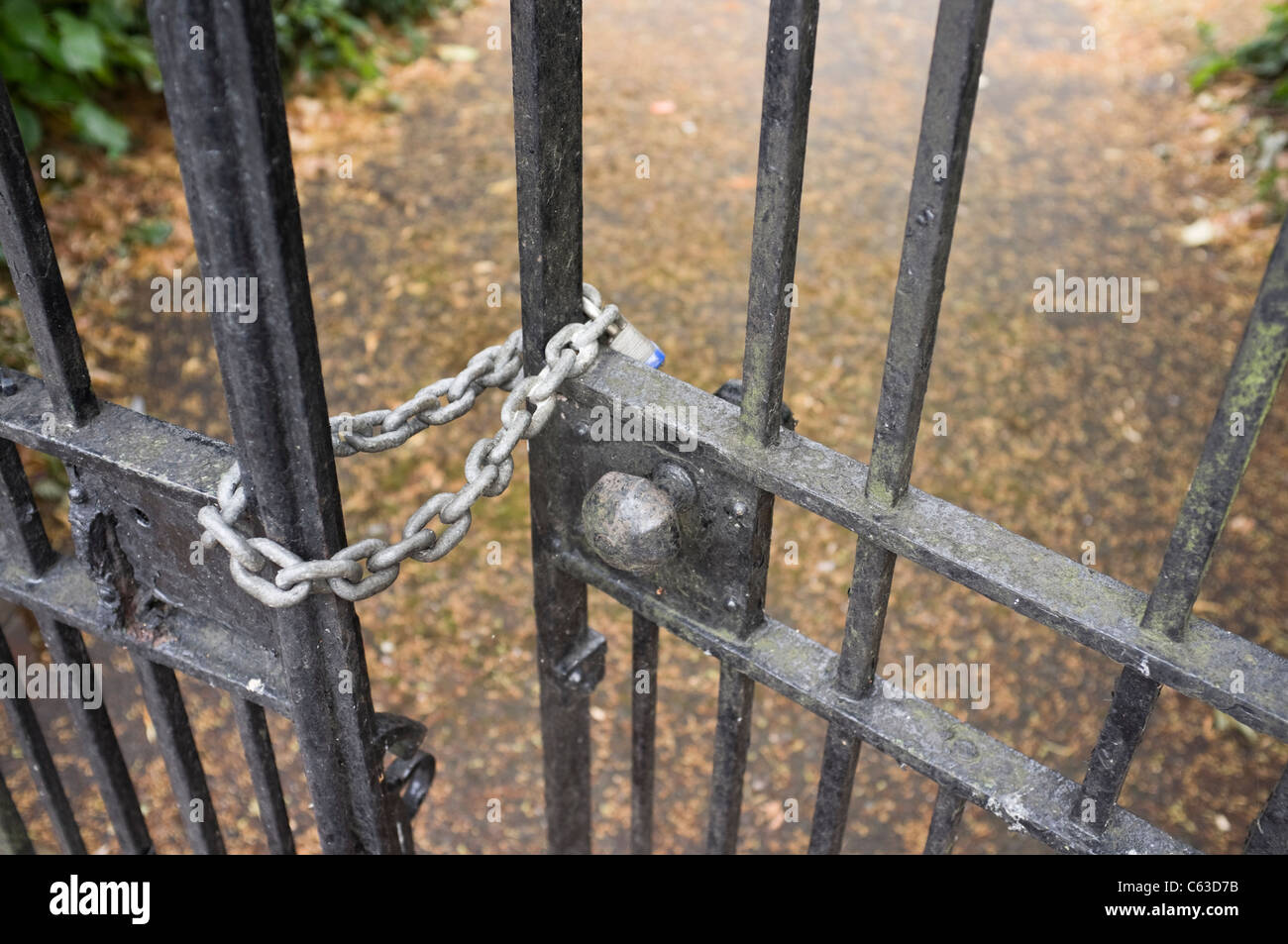 England, UK, Britain. Close-up of padlock on a chain locking wrought iron gates at the entrance to a school Stock Photo